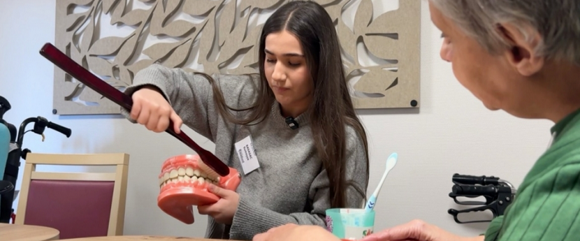 Une élève explique le brossage des dents grâce à un dentier et une brosse géants